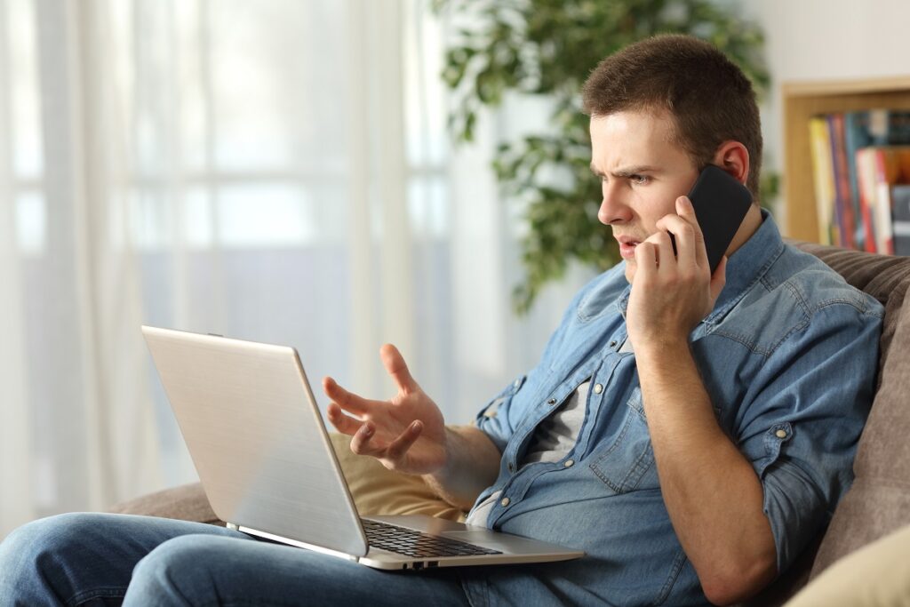 hombre_joven_enojado_hablando_por_telefono_y_viendo_la_computadora-1024x683-1